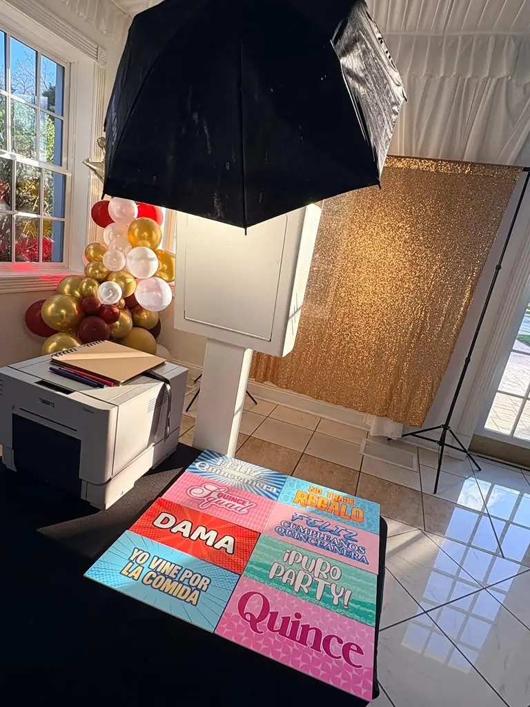 Photo booth and printer set up for a quinceañera with gold balloons